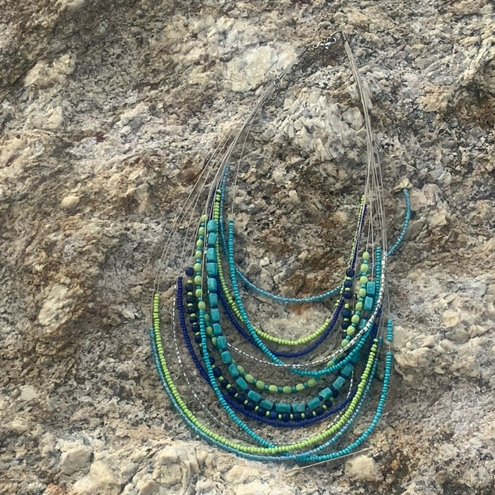 Necklace with multiple strands of beaded wire. Beads are blues and greens.